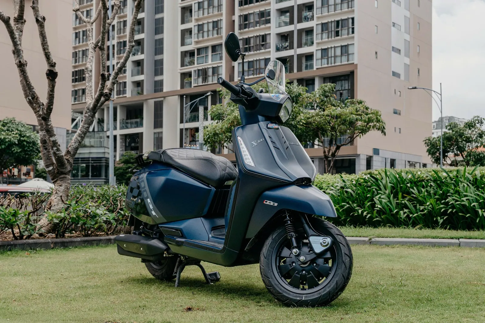 Lambretta X300 GT xanh navy đậu trước hàng cây và toà nhà